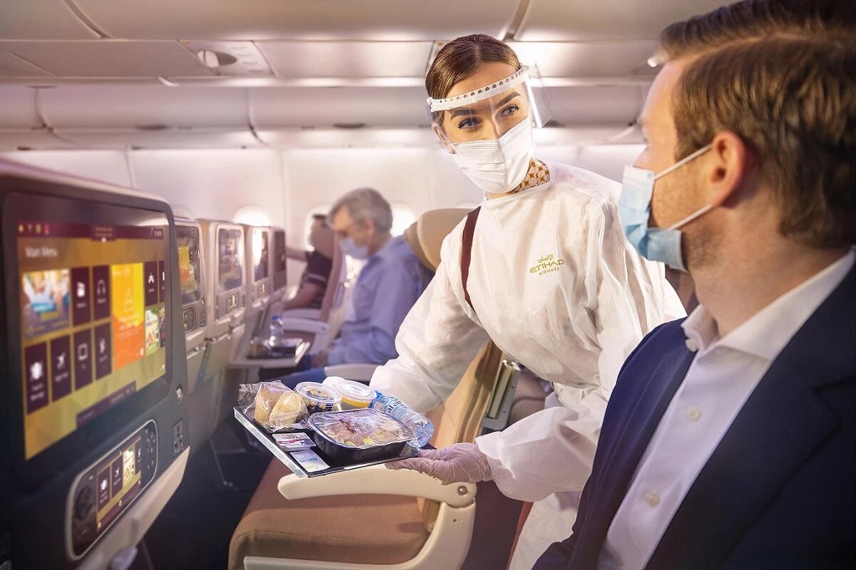 Etihad cabin cabin crew with guest wearing face masks